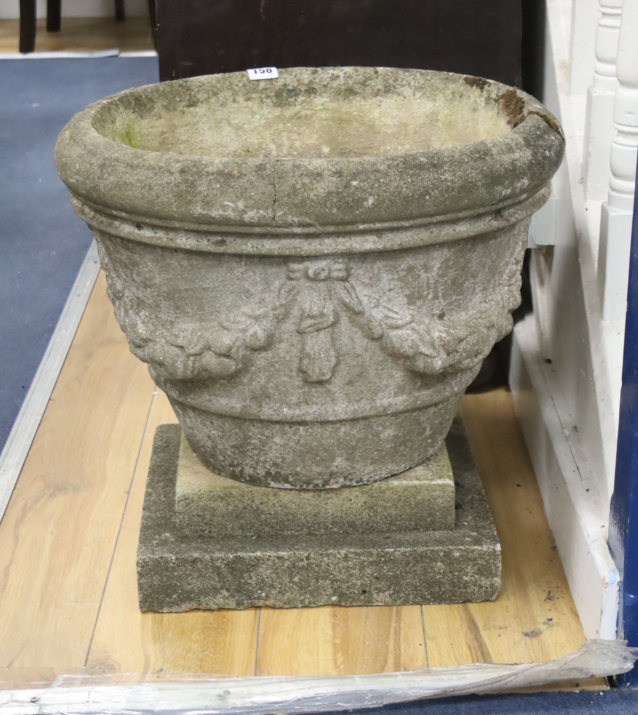 A circular reconstituted stone garden planter on square plinth, diameter 49cm, height 46cm